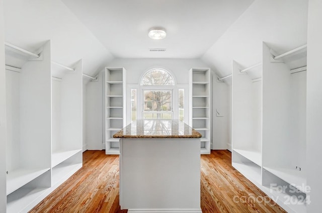 walk in closet with light hardwood / wood-style floors and lofted ceiling