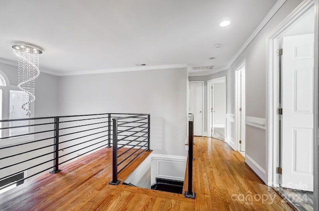 hallway featuring hardwood / wood-style floors, a notable chandelier, and ornamental molding