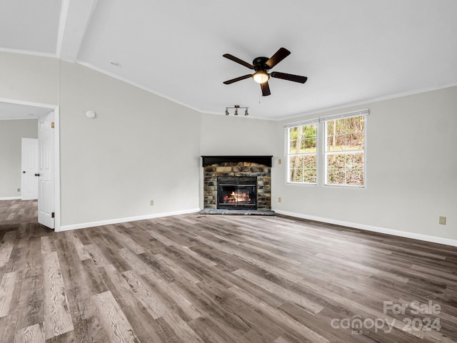 unfurnished living room featuring hardwood / wood-style floors, a stone fireplace, ceiling fan, and ornamental molding