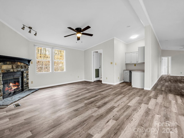 unfurnished living room featuring ceiling fan, light hardwood / wood-style floors, lofted ceiling, a fireplace, and ornamental molding