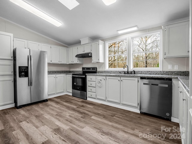 kitchen with sink, light hardwood / wood-style flooring, vaulted ceiling with skylight, appliances with stainless steel finishes, and white cabinetry