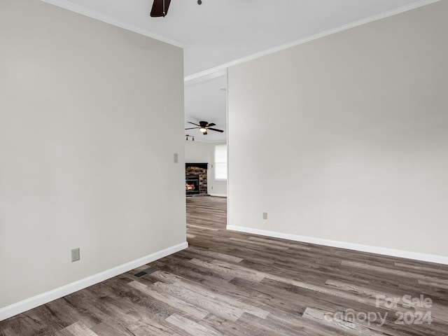 spare room featuring hardwood / wood-style floors, ornamental molding, and a fireplace