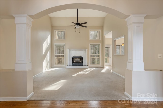 unfurnished living room with ornate columns, ceiling fan, and light colored carpet