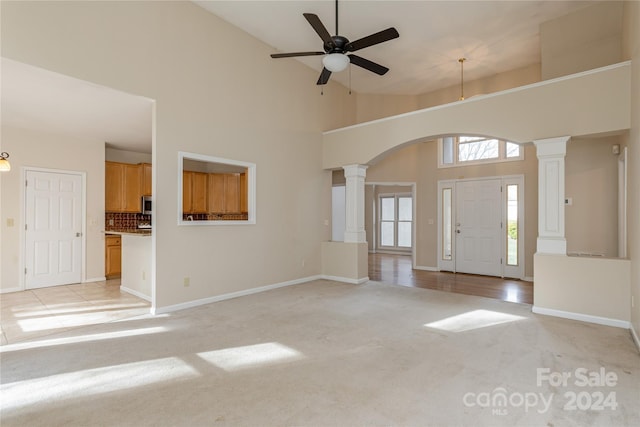 carpeted entryway featuring high vaulted ceiling, ceiling fan, and ornate columns