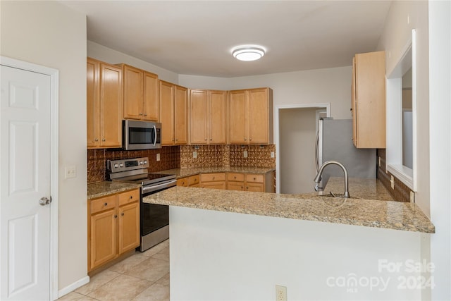 kitchen featuring kitchen peninsula, decorative backsplash, light stone countertops, and stainless steel appliances