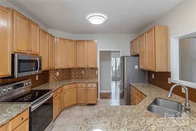 kitchen featuring light tile patterned floors, stainless steel appliances, light brown cabinetry, and sink