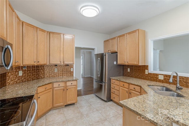 kitchen with light stone countertops, appliances with stainless steel finishes, light brown cabinetry, tasteful backsplash, and sink