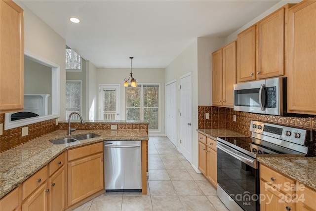 kitchen featuring light stone countertops, sink, stainless steel appliances, a chandelier, and decorative backsplash