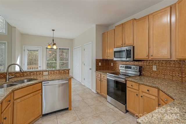 kitchen featuring light stone countertops, sink, stainless steel appliances, an inviting chandelier, and backsplash