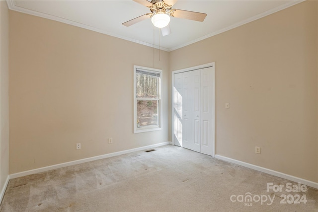 empty room with ceiling fan, light colored carpet, and crown molding