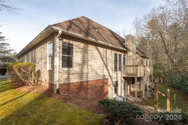 view of side of home with a lawn and central AC