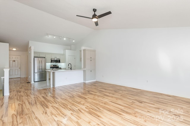 unfurnished living room with ceiling fan, light hardwood / wood-style floors, lofted ceiling, and sink