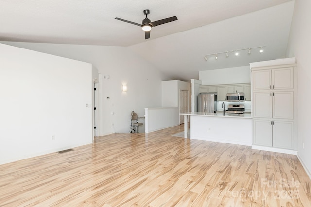 unfurnished living room featuring ceiling fan, light hardwood / wood-style flooring, lofted ceiling, and sink