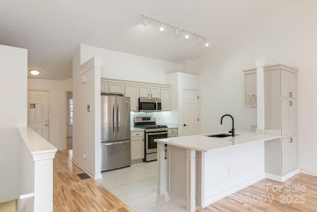 kitchen featuring kitchen peninsula, a kitchen breakfast bar, stainless steel appliances, and sink