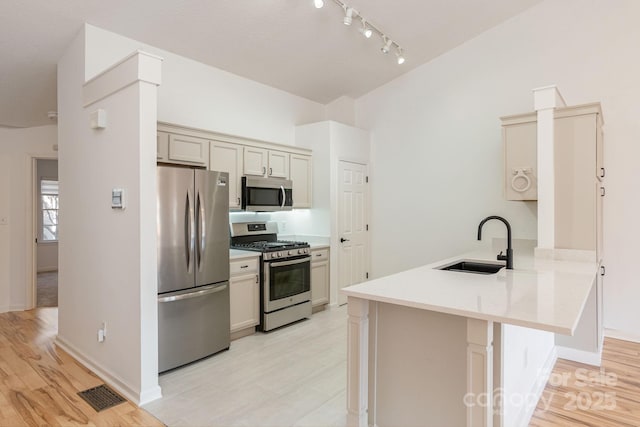 kitchen with cream cabinets, a kitchen breakfast bar, sink, kitchen peninsula, and stainless steel appliances