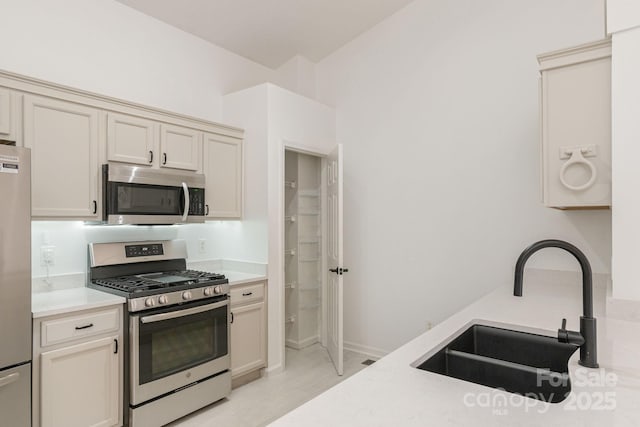 kitchen featuring cream cabinetry, stainless steel appliances, and sink