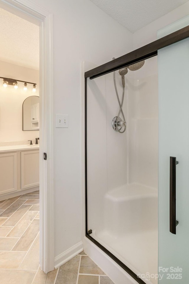 bathroom featuring vanity, a shower with shower door, and a textured ceiling