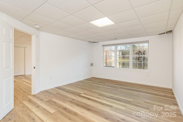 spare room featuring light hardwood / wood-style flooring and a drop ceiling