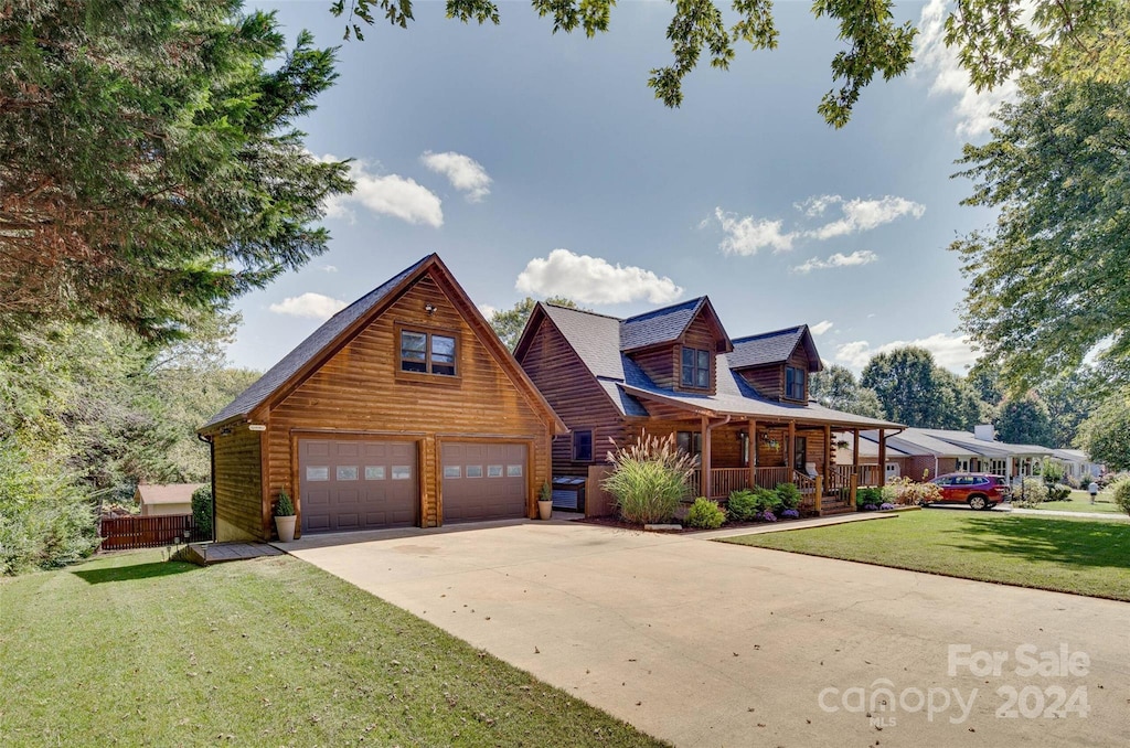 log-style house with an outdoor structure, covered porch, a front yard, and a garage