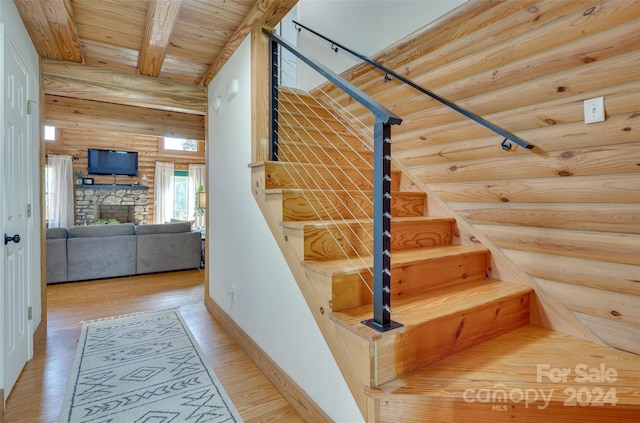 stairs featuring rustic walls, beamed ceiling, wooden ceiling, and hardwood / wood-style flooring