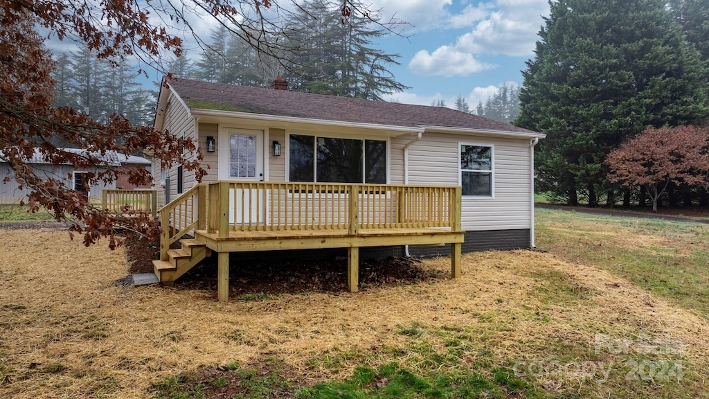 view of front of property featuring a wooden deck and a front lawn