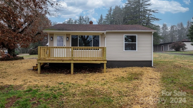 view of front facade with a wooden deck and a front lawn