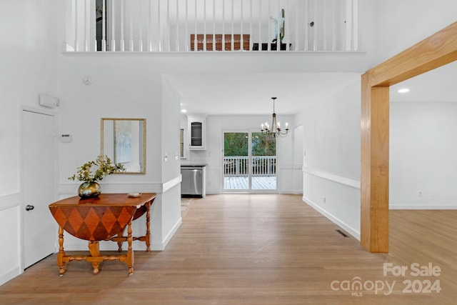 interior space with a chandelier, a high ceiling, and light wood-type flooring