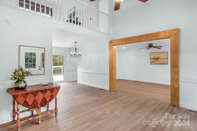 interior space with hardwood / wood-style floors, ceiling fan with notable chandelier, and a high ceiling