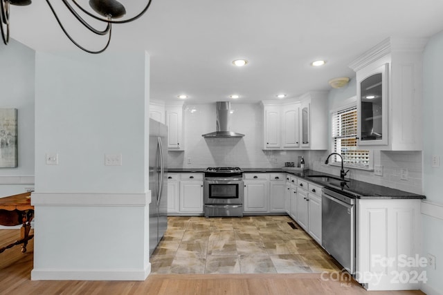 kitchen featuring sink, stainless steel appliances, white cabinetry, and wall chimney range hood