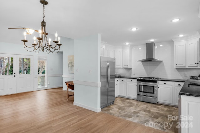 kitchen featuring appliances with stainless steel finishes, light wood-type flooring, wall chimney exhaust hood, pendant lighting, and white cabinets