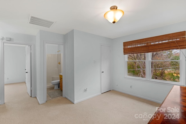 unfurnished bedroom with ensuite bath and light colored carpet