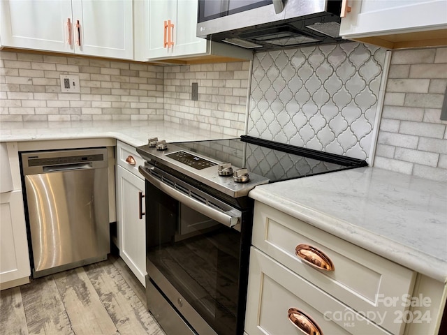 kitchen with light wood-type flooring, stainless steel appliances, and white cabinetry