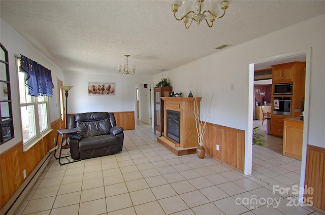 living room with wood walls, a notable chandelier, a textured ceiling, and a baseboard heating unit