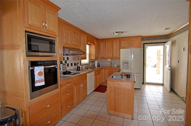 kitchen featuring sink, an island with sink, light tile patterned floors, and appliances with stainless steel finishes