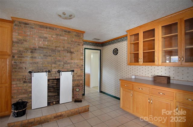 kitchen featuring a barn door, crown molding, light tile patterned floors, and a textured ceiling