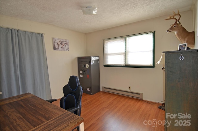 office space with baseboard heating, light hardwood / wood-style flooring, and a textured ceiling