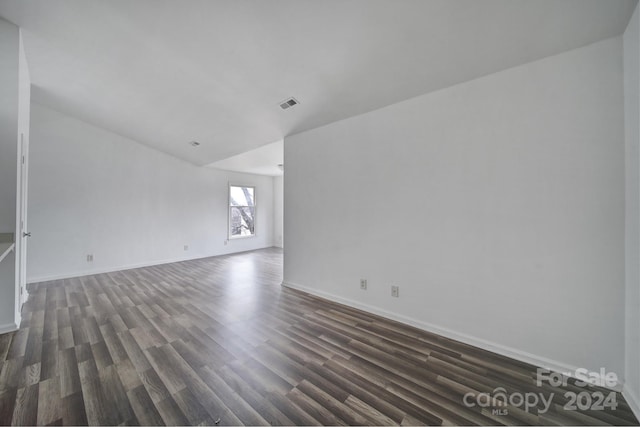 empty room featuring dark hardwood / wood-style floors and vaulted ceiling