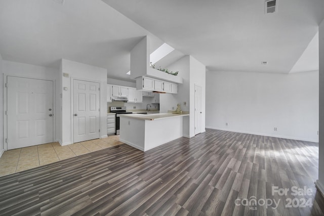 kitchen featuring hardwood / wood-style flooring, white cabinetry, kitchen peninsula, and vaulted ceiling