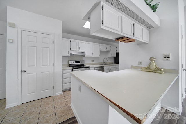 kitchen with sink, kitchen peninsula, light tile patterned floors, white cabinetry, and stainless steel appliances