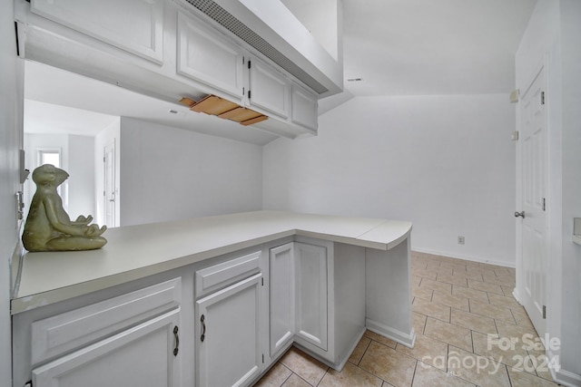 interior space with kitchen peninsula, white cabinetry, and light tile patterned flooring