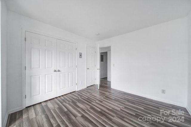 unfurnished bedroom featuring a closet and dark wood-type flooring