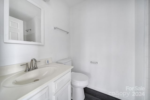 bathroom with wood-type flooring, vanity, toilet, and walk in shower