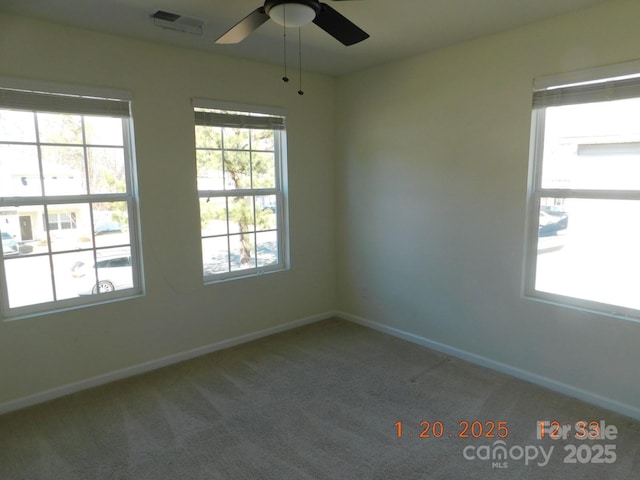 carpeted spare room featuring ceiling fan and a wealth of natural light