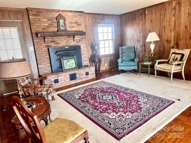 living area featuring crown molding, a fireplace, wooden walls, and a textured ceiling