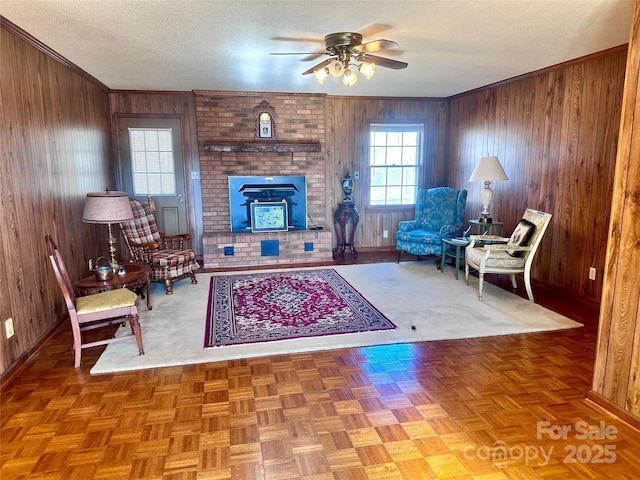 living room featuring crown molding, ceiling fan, a textured ceiling, and wood walls