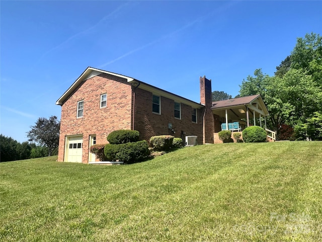 view of property exterior with a chimney, a lawn, a garage, brick siding, and cooling unit