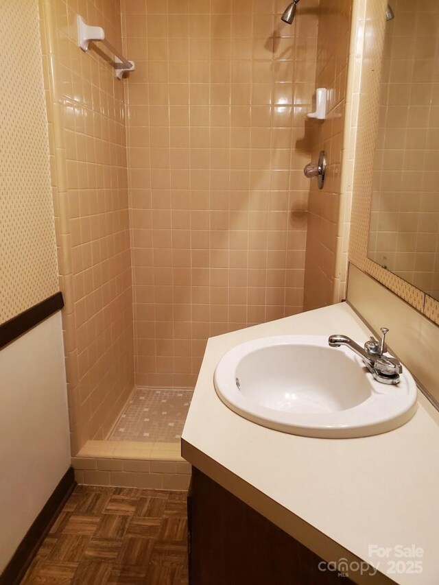 full bathroom with baseboards, a shower stall, and vanity