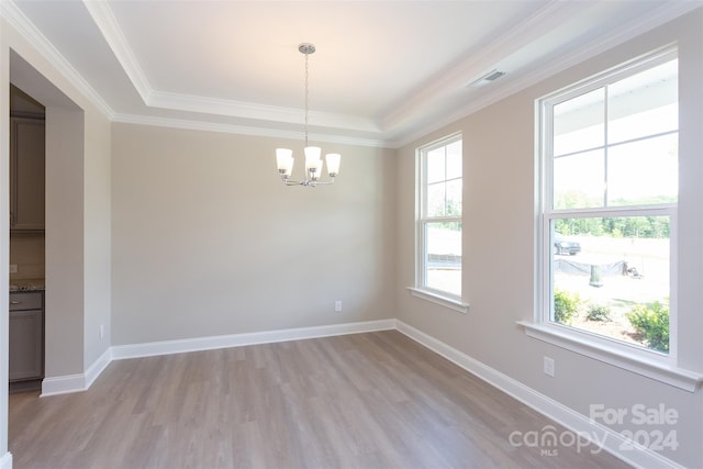 unfurnished room with light wood-type flooring, ornamental molding, and a tray ceiling