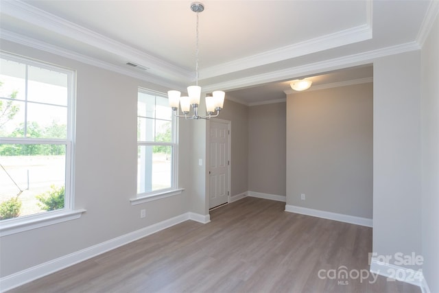 spare room featuring a tray ceiling, crown molding, hardwood / wood-style floors, and a notable chandelier