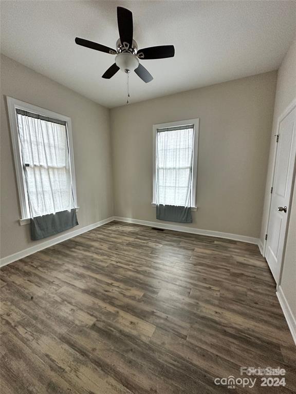 empty room with ceiling fan and dark wood-type flooring